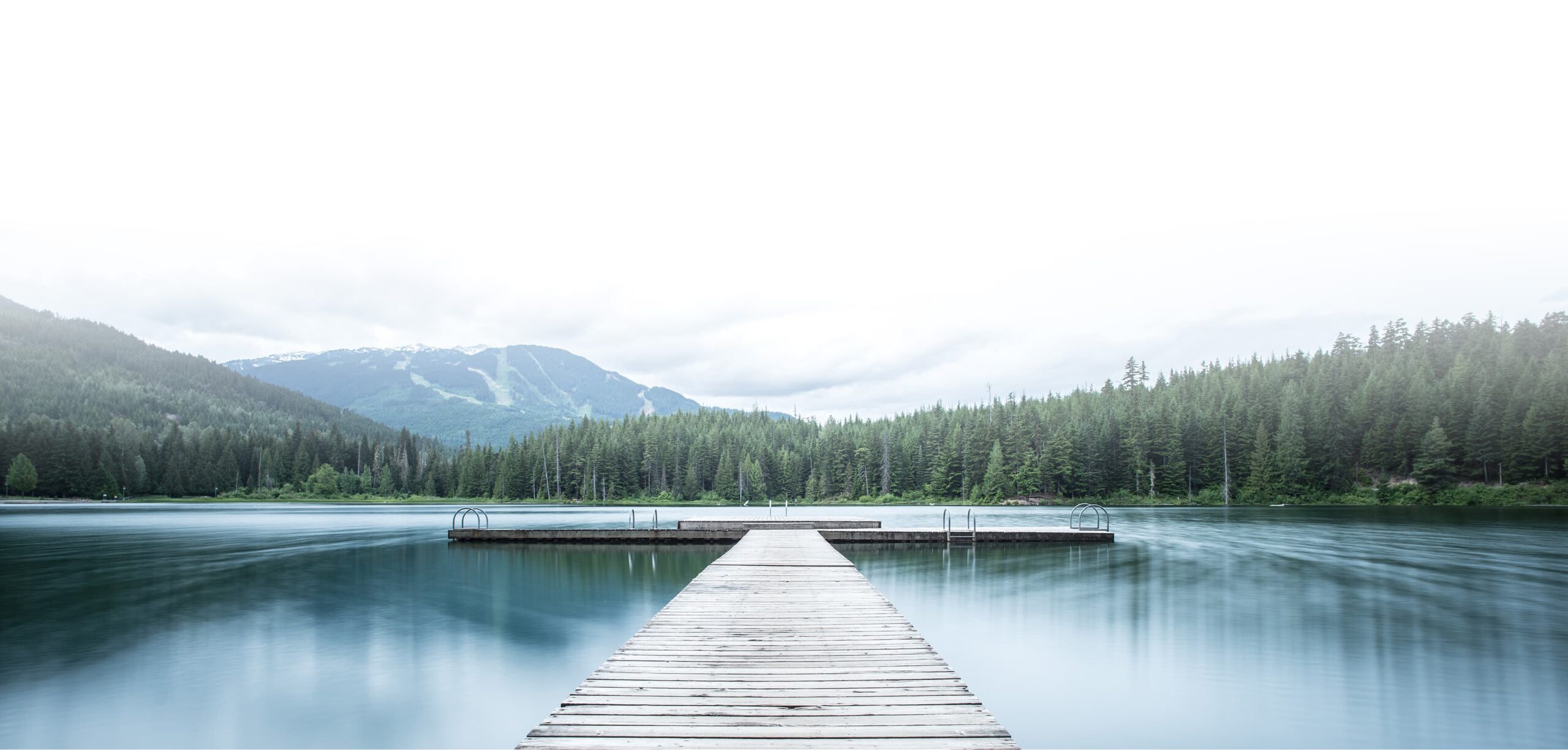 Dock leading out into a lake with mountains in the background